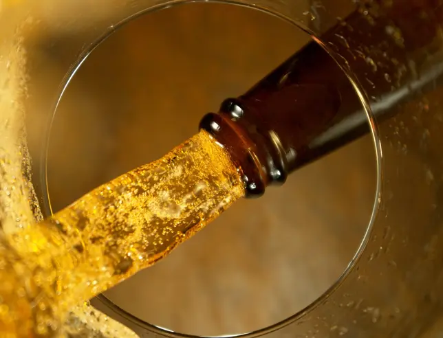Beer being poured from a bottle into a glass, as seen from inside the glass