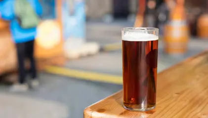 A dark-colored beer glass on a wooden table.