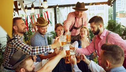 Grupo de pessoas em traje tradicional a brindar com canecas de cerveja.
