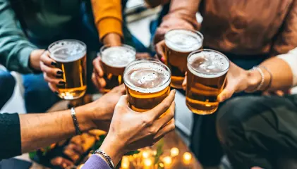 Grupo de pessoas a brindar com copos de cerveja.