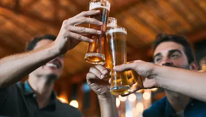 Grupo de pessoas a brindar com copos de cerveja.