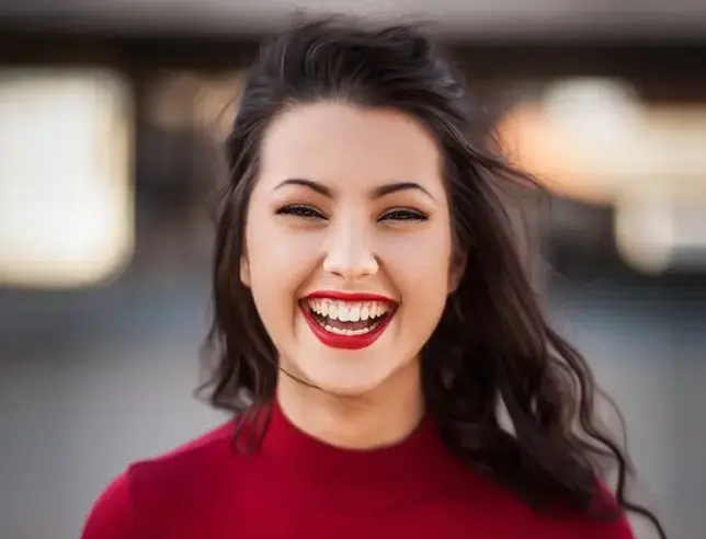 Woman smiling at the camera in an outdoor setting.